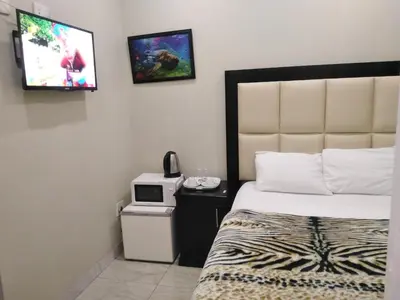 a hotel room with a bed and a tv on the wall at Classic-Lodge in Kempton Park