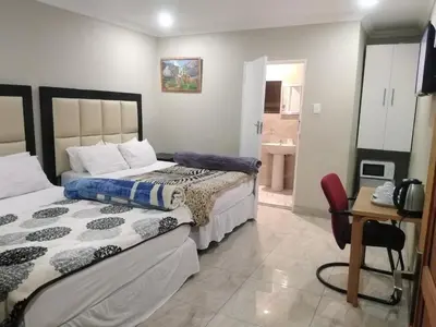 a bedroom with two beds and a bathroom at Classic-Lodge in Kempton Park