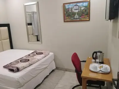 a small room with a bed and a table and a mirror at Classic-Lodge in Kempton Park