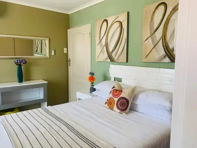a bedroom with a bed and two paintings on the wall at SURVIVOR GUEST HOUSE-Giyani in Giyani