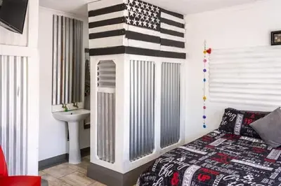 a bedroom with a bed and a bathroom with a american flag wall at MyKhaya-your home away from home in Kempton Park