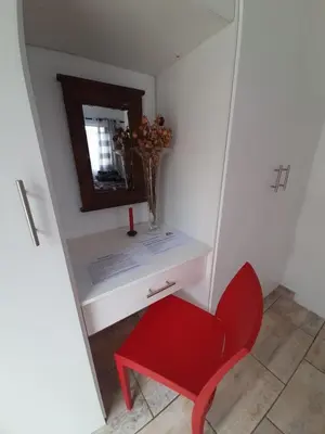a red chair sitting next to a white desk with a mirror at MyKhaya-your home away from home in Kempton Park