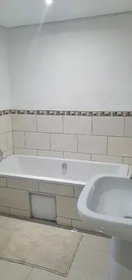 a bathroom with a white tub and a sink at Tertius Lodge And House in Nelspruit