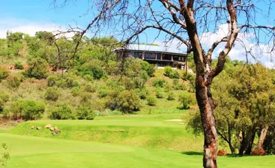 a golf course with a building on a hill at Hillside lodge in Moheme