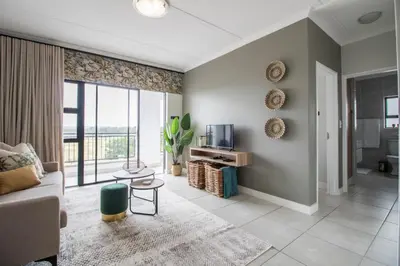 a living room with a couch and a tv at The Blyde - Appartement De Luxe in Pretoria