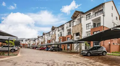 a street with cars parked in front of buildings at The Blyde - Appartement De Luxe in Pretoria