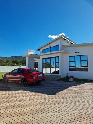 a red car parked in front of a white house at ONNIE GUESTHOUSE in Louis Trichardt