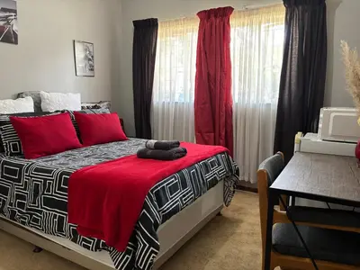 a bedroom with a bed with a red blanket at Bottie's Rock in Pretoria