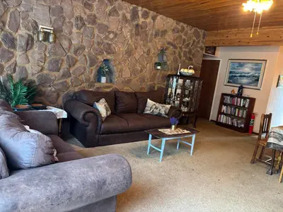 a living room with couches and a stone wall at Bottie's Rock in Pretoria