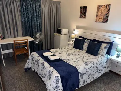 a bedroom with a bed and a table and a desk at Bottie's Rock in Pretoria