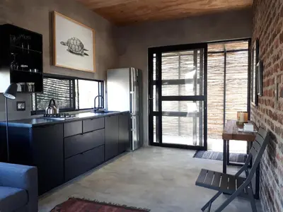 a kitchen with a refrigerator and a table in a room at Terrapin Studio in Marloth Park