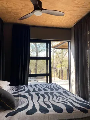 a bedroom with a ceiling fan and a large window at Terrapin Studio in Marloth Park