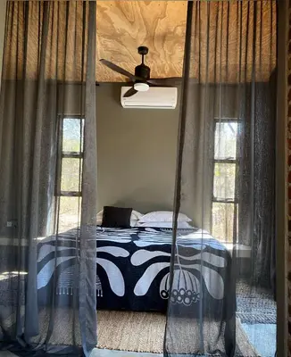 a bedroom with a bed with a ceiling fan at Terrapin Studio in Marloth Park
