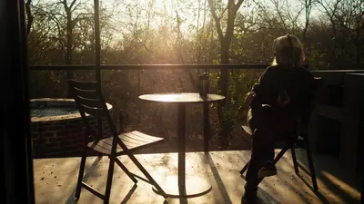 a woman sitting at a table on a balcony at Terrapin Studio in Marloth Park