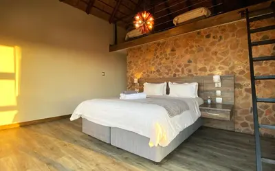 a bedroom with a bed and a brick wall at Shammah lodge Mabalingwe Nature Reserve in Mabula
