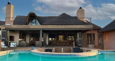 a house with a swimming pool in front of a house at Shammah lodge Mabalingwe Nature Reserve in Mabula