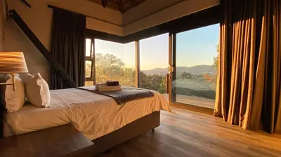 a bedroom with a bed and a large window at Shammah lodge Mabalingwe Nature Reserve in Mabula