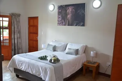 a bedroom with a white bed with a stuffed animal on it at Muqurati Lodge - Dinokeng Game Reserve in Klipdrift