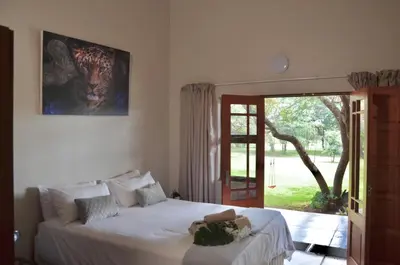 a bedroom with a bed and a sliding glass door at Muqurati Lodge - Dinokeng Game Reserve in Klipdrift