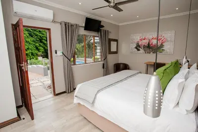 a bedroom with a white bed and a sliding glass door at Vinique Guesthouse in Nelspruit