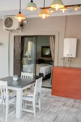 a dining room with a table and chairs and a bedroom at Vinique Guesthouse in Nelspruit
