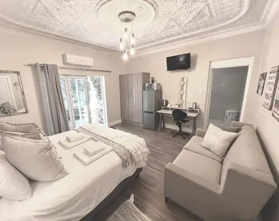 a bedroom with a bed and a couch and a desk at Buffels Place Guesthouse in Pretoria