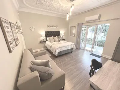a living room with a bed and a couch at Buffels Place Guesthouse in Pretoria