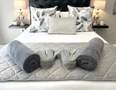 a bed with grey blankets and pillows on it at Buffels Place Guesthouse in Pretoria