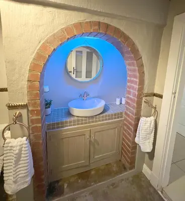a bathroom with a sink and a brick arch at Buffels Place Guesthouse in Pretoria