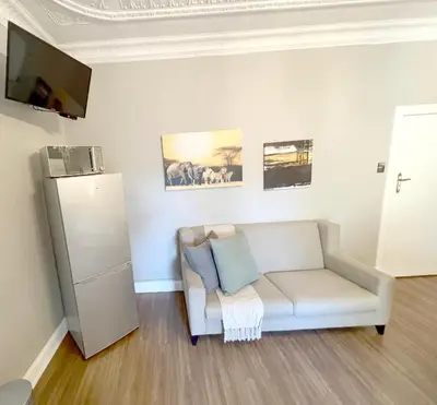 a living room with a white couch and a refrigerator at Buffels Place Guesthouse in Pretoria