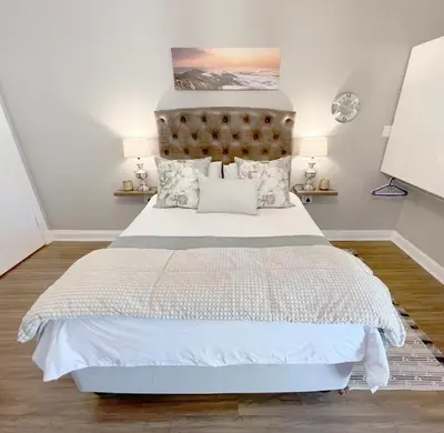 a bedroom with a large bed with white sheets and pillows at Buffels Place Guesthouse in Pretoria