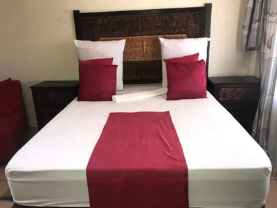 a bedroom with a large bed with red pillows at Kaste Guesthouse Secunda in Secunda