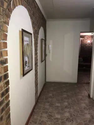 a hallway with a brick wall and two pictures on the wall at Kaste Guesthouse Secunda in Secunda