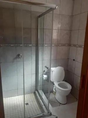 a bathroom with a toilet and a glass shower stall at Hazelonz Bed &Breakfast in Pretoria