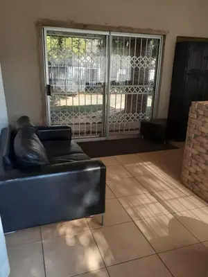 a black leather couch in a living room with a sliding glass door at Hazelonz Bed &Breakfast in Pretoria