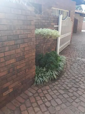 a brick wall with a white gate and some plants at Hazelonz Bed &Breakfast in Pretoria