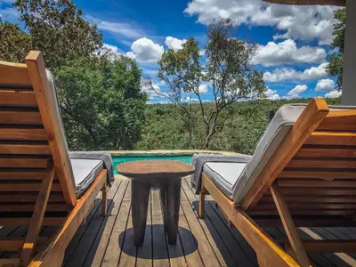 a table and chairs on a deck with a pool at Laluka Safari Lodge - Welgevonden Game Reserve in Welgevonden Game Reserve