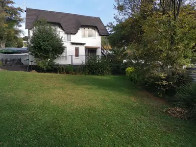 a white house with a fence and a yard at Erasmus manor Guest House in Pretoria