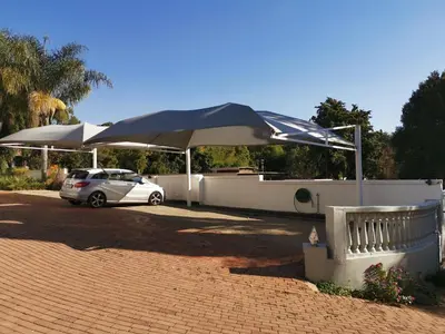 a car parked under an umbrella in a driveway at Erasmus manor Guest House in Pretoria