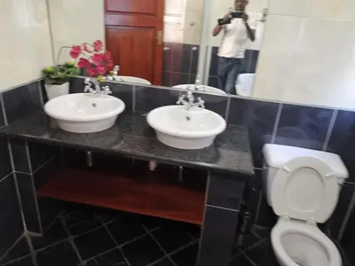a person taking a picture of a bathroom with two sinks at Erasmus manor Guest House in Pretoria