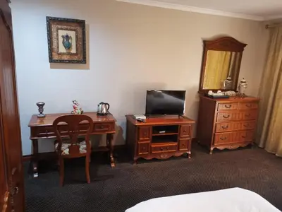 a bedroom with a desk and a tv and a dresser at Erasmus manor Guest House in Pretoria
