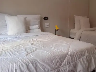 a white bed with white sheets and pillows at Kaste guesthouse Tzaneen in Tzaneen