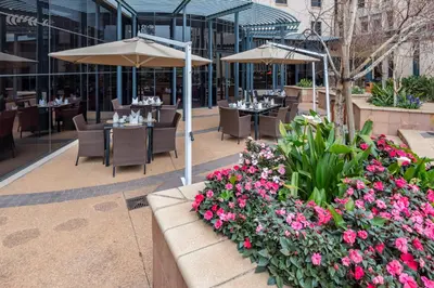 a restaurant with tables and chairs and flowers at City Lodge Hotel Hatfield, Pretoria in Pretoria