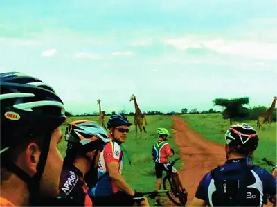 a group of people riding bikes on a dirt road with giraffes at Sondela Nature Reserve & Spa Moselesele Tents in Bela-Bela