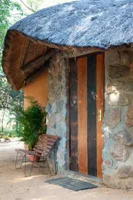 a building with a wooden door and a chair outside at Shumba Safari Bush Camp in Hoedspruit