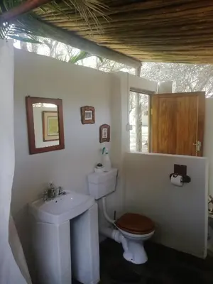a white bathroom with a toilet and a sink at Shumba Safari Bush Camp in Hoedspruit