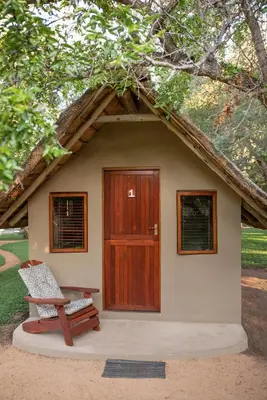 a small house with a wooden door and a bench at Shumba Safari Bush Camp in Hoedspruit