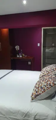 a bedroom with a white bed and a purple wall at TERTIUS LODGE in Nelspruit