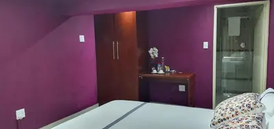 a purple room with a bed and a table at TERTIUS LODGE in Nelspruit