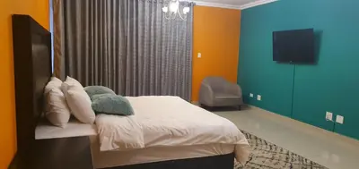 a bedroom with a bed and a tv in it at TERTIUS LODGE in Nelspruit